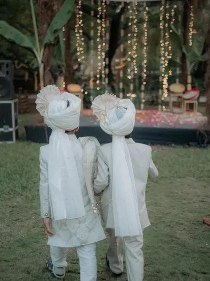 Two young boys dressed in matching traditional outfits, walking towards the ceremony. This shot from behind tells a story of friendship and participation in the big day.