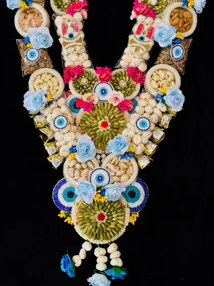 This grand dry fruit garland is a true statement piece. It's lavishly decorated with nuts, evil eye beads, and flowers, making it a luxurious and memorable gift for Holi.