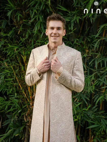 A happy client showcasing the full length of the open sherwani. The way it drapes over the kurta creates a layered, sophisticated look that is both traditional and refreshingly modern.
