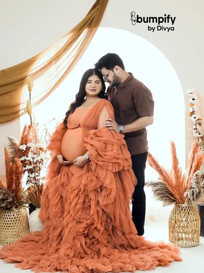 The rich, earthy tones of this ruffled gown and our boho studio setup create a warm and dramatic maternity portrait.