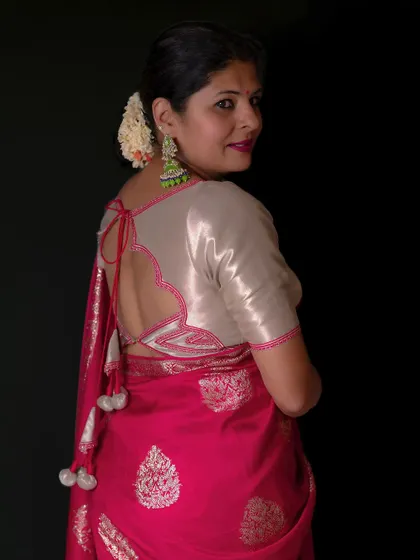 A custom-designed blouse back with a heart-shaped cutout and decorative tassels, adding a playful touch to a pink Banarasi saree.