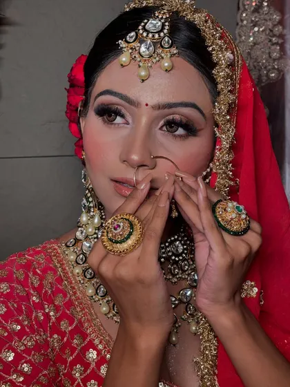 A close-up of the bride's delicate features, with a focus on the eye makeup, nose ring, and the beautiful hand-to-forehead jewelry.