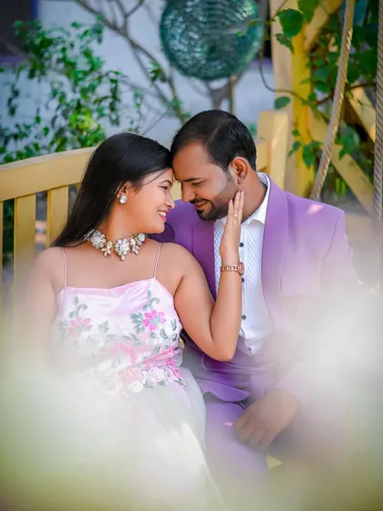 An intimate close-up of a couple sharing a tender moment on a bench. The soft focus and warm lighting create a dreamy, romantic atmosphere for this pre-wedding portrait.