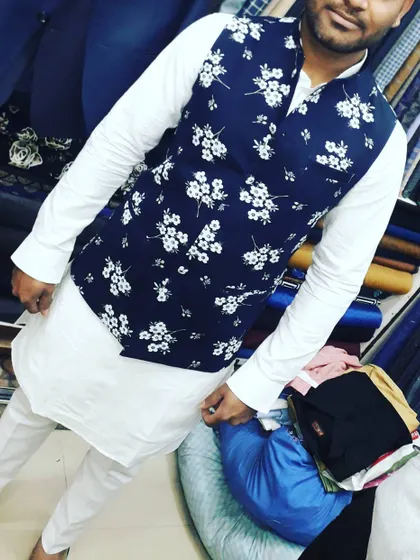 A client looking sharp in a classic white kurta pajama, elevated by a navy blue floral print Nehru jacket. This is a popular choice for daytime functions.
