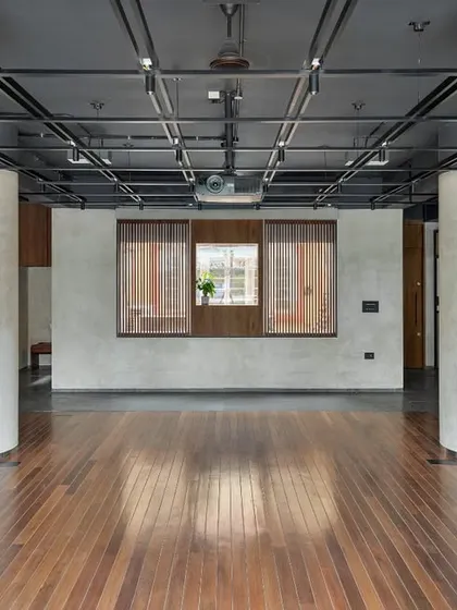 An unobstructed view of the central stage area highlights the clean expanse of wood flooring, designed to accommodate a wide range of activities. The large, open space is framed by structural columns and varied textures, creating a dynamic yet balanced architectural composition.