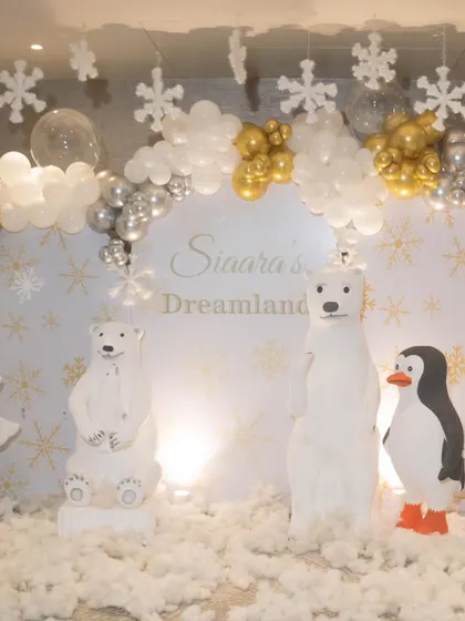 The main backdrop for the winter wonderland theme, featuring polar bear props, a personalized "Dreamland" sign, and a cascade of white, silver, and gold balloons.