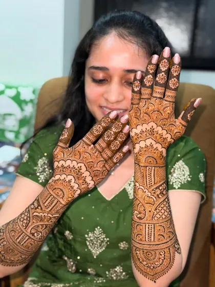 This beautiful bride is all smiles as she shows her intricate mehendi. The design is a lovely mix of traditional patterns, perfect for her wedding celebrations.