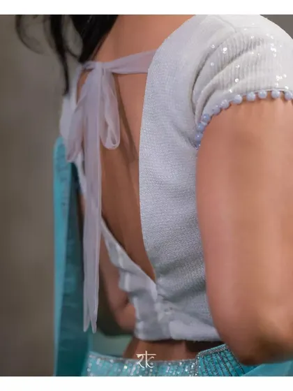 The back of the sequin blouse features a chic tie-back design, adding a final touch of modern glamour.