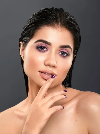 A full-view portrait from a collaboration, showcasing a striking purple eyeshadow look and wet-look hair. The model's pose is confident and direct, resulting in a powerful and modern beauty shot.