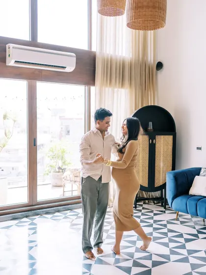 A wider angle of the couple dancing in their living room. This shot captures the full environment, showing their beautiful home and their joyful interaction within it.