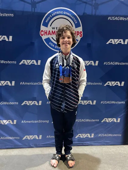 Asher proudly displays his medals from Western Nationals, where he placed on Floor, Pommel, P-bars, and High Bar.