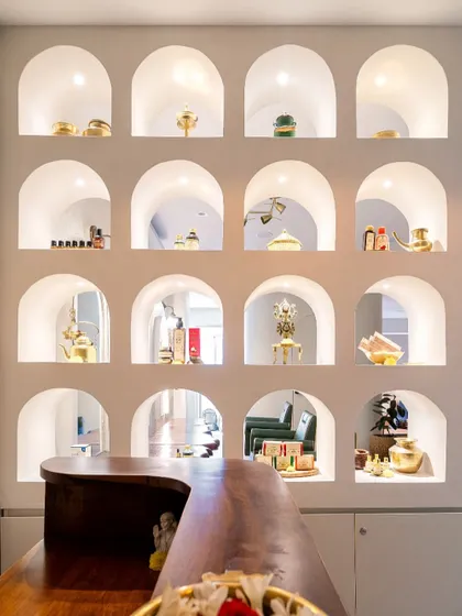 The reception area features this stunning wall of illuminated arched niches, designed to showcase the spa's premium products. This not only serves as a beautiful focal point but also as an elegant retail display, blending commerce with art.