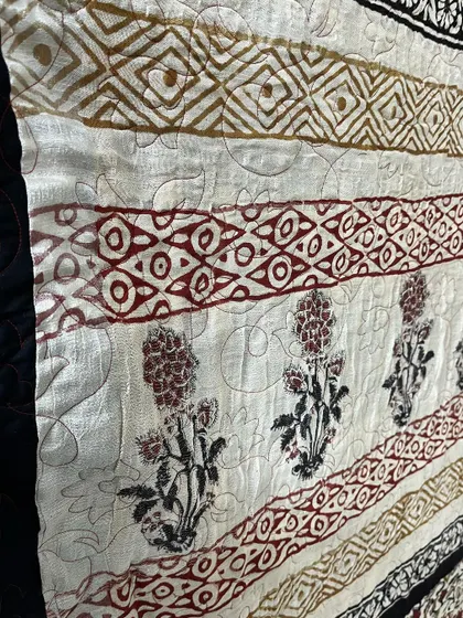 A close-up showing the delicate floral and geometric patterns of a saree, preserved forever in a custom quilt.