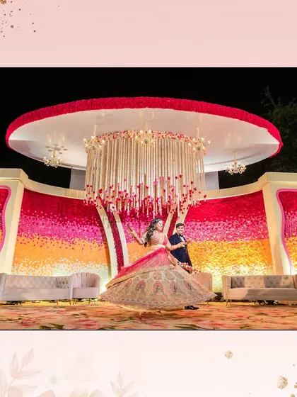 A vibrant and colorful floral stage for a reception. The ombre flower wall and grand chandelier create a stunning backdrop for the happy couple.