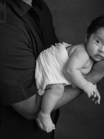 A close-up of the father and baby, where the black and white format draws attention to the baby's curious gaze.