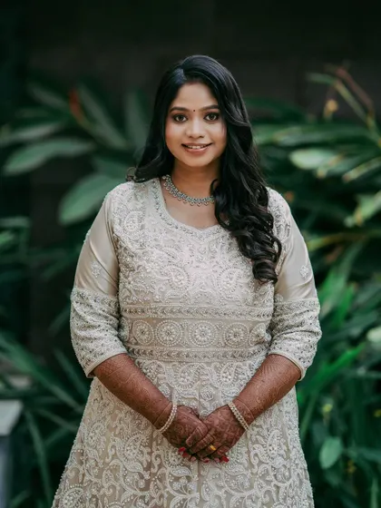 A full-length portrait of Sowmya in her elegant white reception gown.