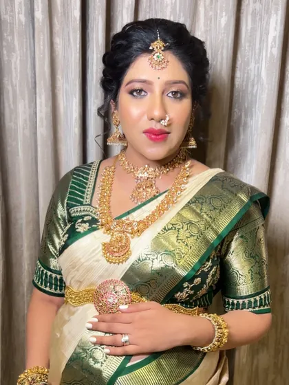 A full portrait of the mom-to-be at her baby shower. The classic drape of the white and green silk saree, paired with temple jewelry, creates a timeless and graceful look.