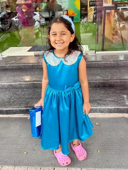 A happy customer looking radiant in her blue satin dress. The sequined collar adds just the right amount of sparkle for a birthday party or special outing.