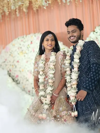 Jagruthi and her husband making a grand entrance at their reception amidst a cloud of smoke. Her embroidered lehenga and diamond jewelry create a truly magical look.
