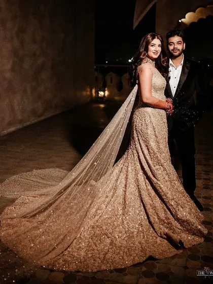 The bride looks like a fairytale princess in her shimmering Tarun Tahiliani gown with a long, flowing cape, perfect for a grand sangeet entrance.