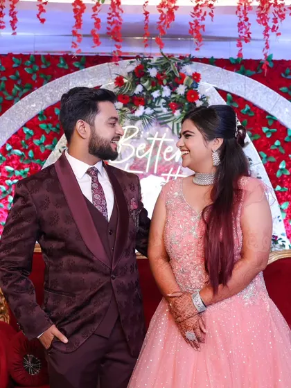 A candid moment of laughter and love. The couple looks at each other, sharing a private joke, against a vibrant floral backdrop.