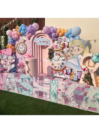 A vibrant and detailed stage for an Alice in Wonderland party, with large character cutouts and a personalized name display.