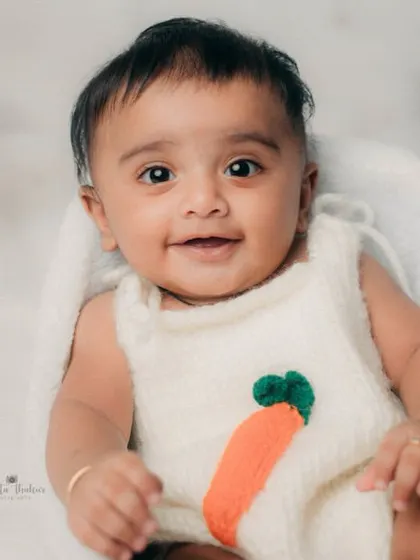 This 5-month-old's smile can light up any room. The simple, cloudy white background and carrot-themed outfit make his expression the star of the show.
