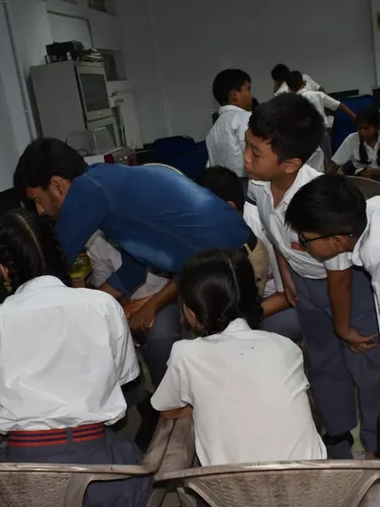 Students gather around a computer, collaborating on a coding challenge with the help of an instructor.