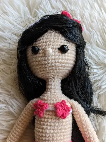 A close-up of the mermaid doll's face and her pink seashell top.