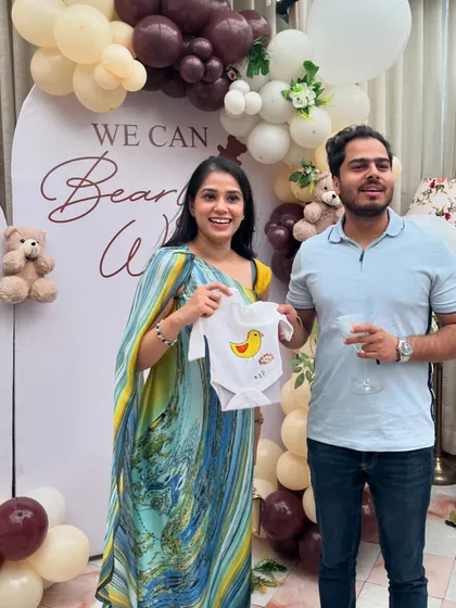 The happy parents-to-be showing off a cute, hand-painted duck onesie made by one of their guests. These creations become cherished keepsakes.