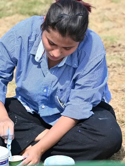 Mixing paints on the ground during the Gurujal mural project. This is the unglamorous, hands-on reality of being a muralist. It's about being close to the materials and the earth, preparing the colors that will soon bring a wall to life.