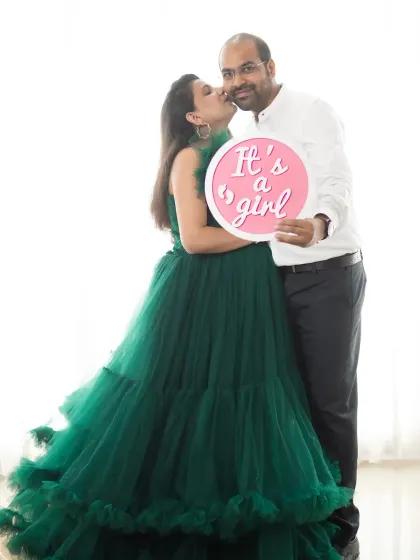 A sweet kiss for the proud dad-to-be as he holds the "It's a girl" sign. A perfect way to celebrate and share their happy news.