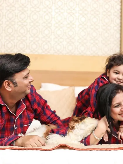 A playful family photo on the bed, with the toddler smiling brightly. This image shows the happy and relaxed atmosphere of an in-home family session.