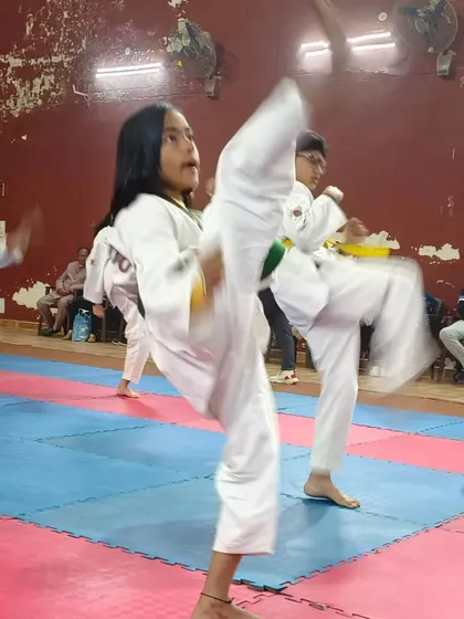 Young students in a group Taekwondo class practicing their high kicks together. Repetition and group energy help everyone improve their form.