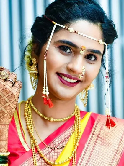 A radiant bridal portrait showcasing the intricate details of the mundavalya, nath, and detailed mehendi design.