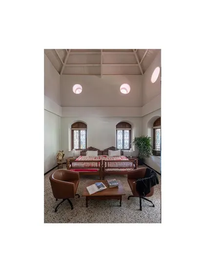 A seating arrangement in a high-ceilinged room with original oculi windows. We used a mix of inherited and contemporary furniture to create a functional and eclectic space.