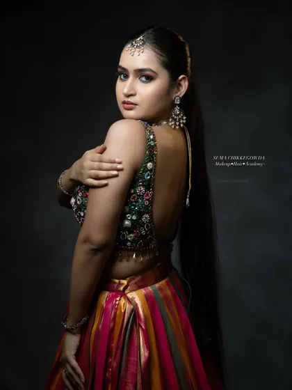 A stunning look for a Sangeet or reception, featuring a heavily embellished blouse and a multi-colored lehenga. The makeup is kept glamorous with a focus on defined eyes and contoured features.