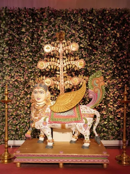 A bejeweled Kamadhenu, the sacred cow, stands as a centerpiece. This piece was created by three talented artists, combining copper engraving, pattachitra painting, and wood carving to represent prosperity and divinity.
