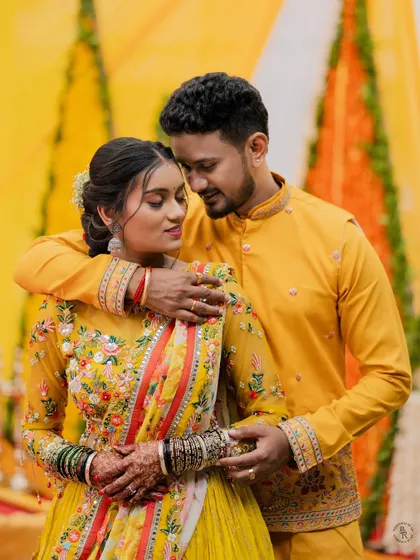 A lovely portrait of a couple in matching yellow outfits, sharing a tender moment during their Haldi or Mehendi ceremony.