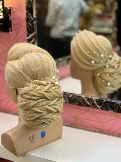 A side view of the twisting and pulling bun, showing its intricate texture and reflection in the mirror.