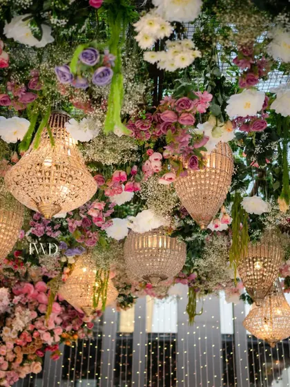 The interplay of light and flowers in our upside down garden. The warm glow from the chandeliers illuminates the delicate petals, creating a romantic and magical ambiance for an evening ceremony.