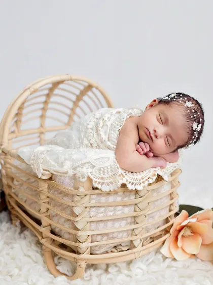 A peaceful portrait of a newborn in a beautiful wicker bassinet. The simple white background and soft textures create a timeless and angelic look.