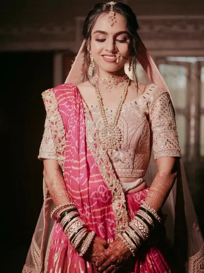 The bride's serene expression captured perfectly. The soft pink makeup complements her Bandhani dupatta and pastel lehenga.
