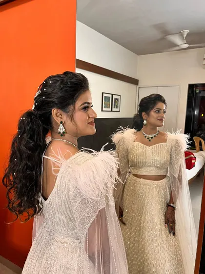 A crown of curls fit for a queen. This high ponytail with voluminous curls and pearl accessories is a statement look for a modern bride.