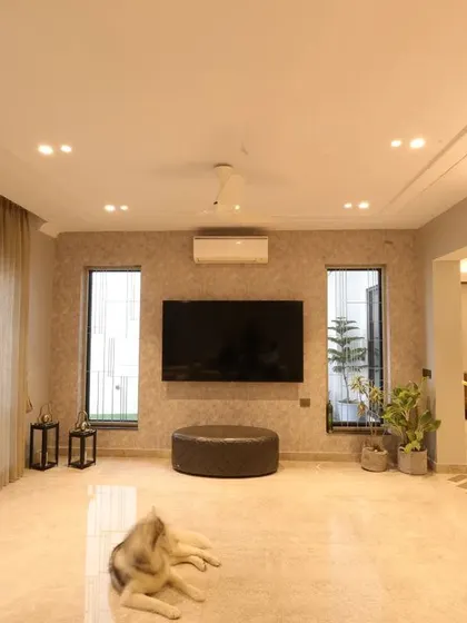 The spacious layout of the drawing room, featuring a large TV and minimal furniture to maintain a clean, uncluttered look.