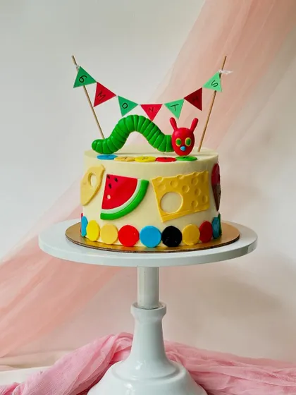Inspired by the classic children's book, this Very Hungry Caterpillar cake is bright and colourful. It features the caterpillar on top and the foods he ate along the sides, all made from fondant.