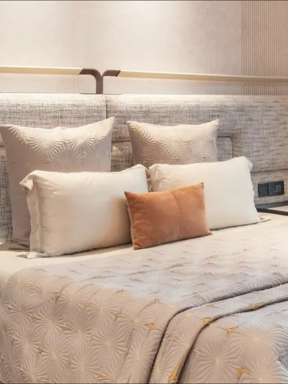 A detailed shot of the custom headboard, showcasing the textured fabric and elegant metal hardware. Every element is designed to contribute to the room's overall sense of refined comfort.