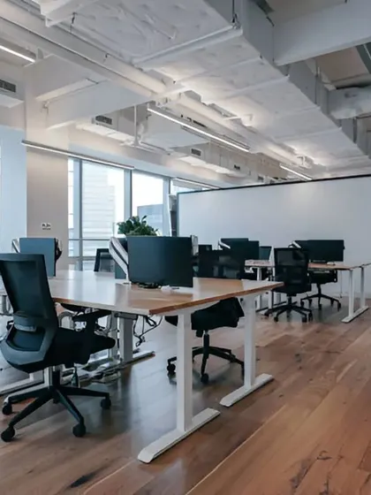A wide shot of a 6,000 sq. ft. corporate office in Gurgaon, showcasing an open-plan layout with hardwood floors and exposed ceilings. The design maximizes natural light from the large windows.