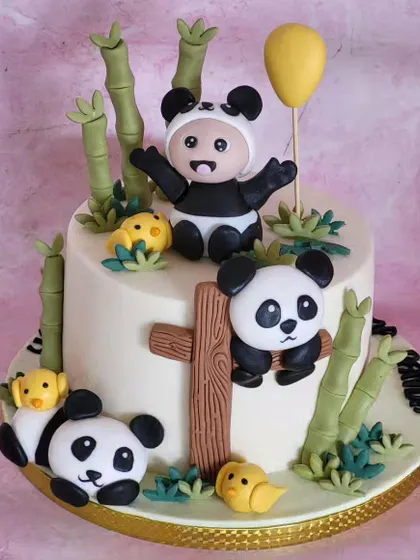 A sweet panda-themed cake for a first birthday. The design includes multiple adorable pandas and bamboo stalks, all made from fondant.