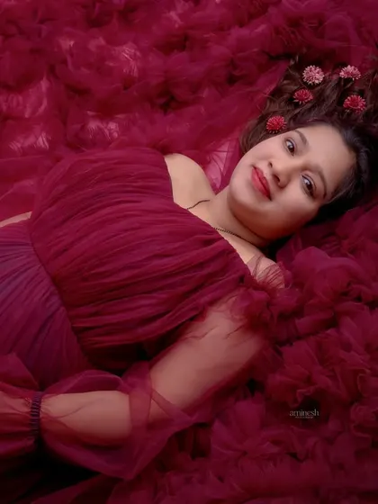 Another creative use of fabric, this overhead shot envelops the mother-to-be in a sea of rich, maroon ruffles. The flowers in her hair add a delicate, personal touch.
